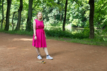 Young woman strolls through a summer park with her agama lizard on a delicate leash