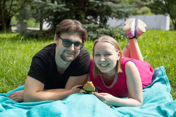 Young couple relaxes on an azure picnic blanket in the summer park, their pet agama lizard basking contentedly beside them