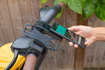 Mature Man is making a contactless payment with his smartphone for the rental of a public sharing...