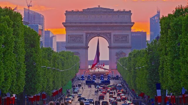 Arc de Triomphe against the backdrop of a beautiful sunset. French flag in the wind in the triumphal arch. Paris, France