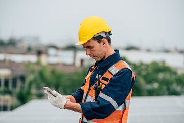 Worker in safety gear checking smartphone while on rooftop during overcast day in urban area