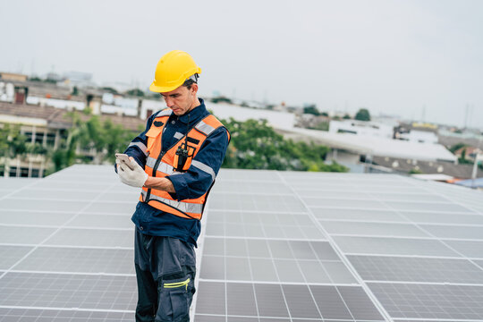 Technician checks data on smartphone while inspecting solar panels at urban rooftop site