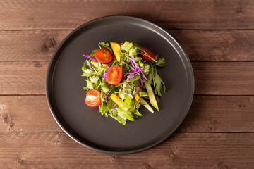 Plate with salad.A close-up view reveals a well-composed salad on a dark, round 