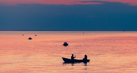 Silhouette of couple in boat at ocean on sunset time