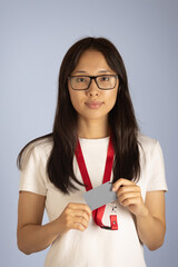 Girlis holding a grey identification card or badge attached to a red lanyard around her neck