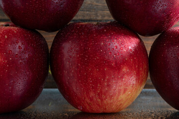 foto de cinco manzanas rojas apiladas con gotas de agua y fondo de madera oscura