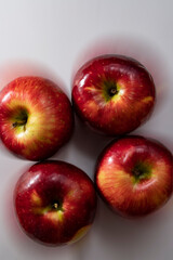 foto de cuatro manzanas rojas en el centro de la imagen sobre fondo blanco difuminado 