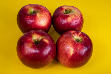 foto de cuatro manzanas rojas en el centro de la imagen sobre fondo amarillo difuminado 