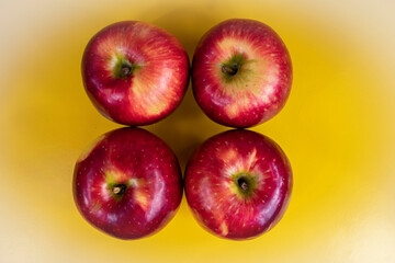 foto de cuatro manzanas rojas en el centro de la imagen sobre fondo amarillo difuminado 