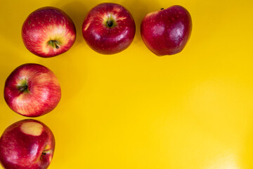 foto de cinco manzanas rojas sobre fondo amarillo en forma de ele