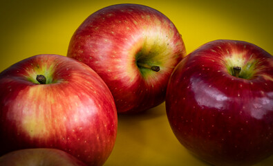 foto de tres manzanas rojas sobre fondo amarillo y bordes difuminados 