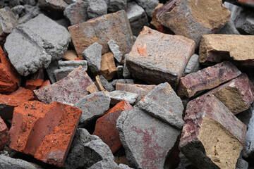 Pile of various broken bricks and pieces of concrete forming a construction waste heap, showcasing different colors and textures.