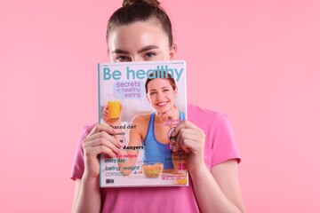 Woman with lifestyle magazine on pink background