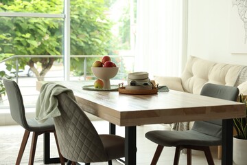 Wooden table, chairs, sofa and decor in dining room. Interior design