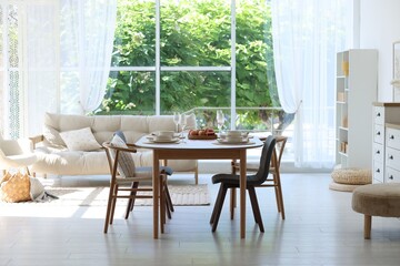 Beautiful table setting, chairs and decor in dining room. Interior design