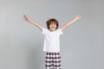 Cute little boy in pajamas on grey background