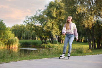 Beautiful young woman roller skating in park