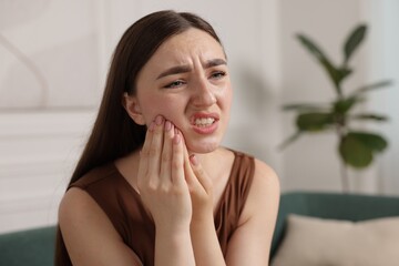 Young woman suffering from toothache at home