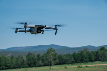 drone captures aerial views as it hovers above lush green field. background features rolling hills...