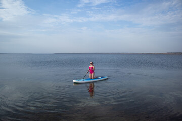 Woman on a sup board with paddle. Copy space. Concept of sup boarding