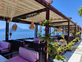 Beautiful horizontal photography concept image picture of a restaurant with tables by the sea view with blue sky golden sand sunlight summer vibes vacation palm trees wallpaper ultra high hd quality 