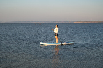 Young Woman Relaxing on Stand Up Paddle Board in Calm Lake. Summer Water Sport, Outdoor Adventure,...