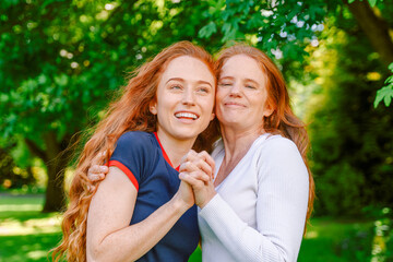 Mother and daughter enjoying a sunny day in a lush park while sharing joyful moments and laughter...