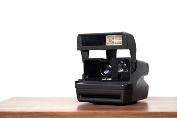An instant camera instantly develops photos on a wooden table. Vintage camera concept. Photography concept. 
Space for text.