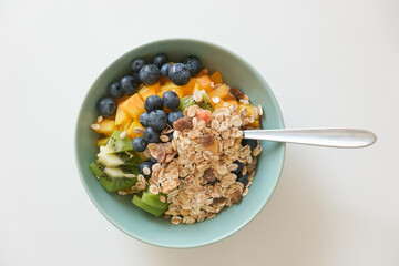Healthy breakfast bowl with granola, fresh blueberries, mango, and kiwi, offering a nutritious and colorful start to the day.
