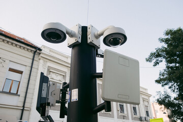 Security cameras on pole monitoring urban street with buildings in background under clear sky