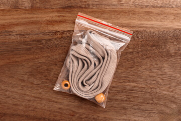 Plastic transparent pack with new brown shoe laces on wooden table