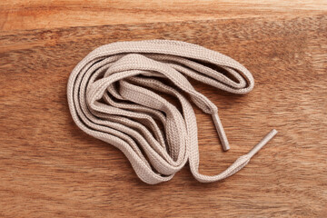 Beige shoe laces on wooden brown table close-up. Top view