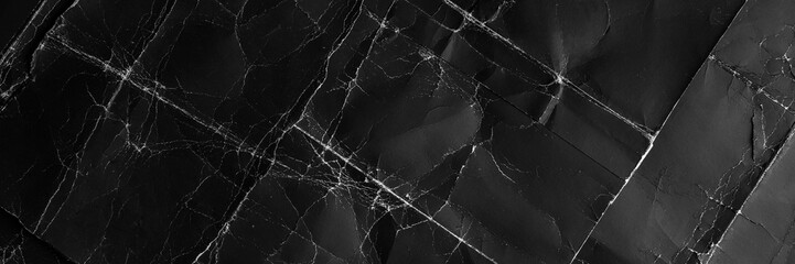 Old black paper background with worn folds and aged wrinkles on dark cardboard. Abstract grunge poster surface