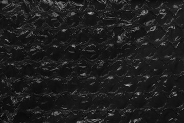 Black abstract background of packaging bubble wrap. Dark soft protective surface