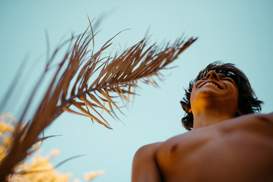 Teen boy smiling near palm tree on sunny day