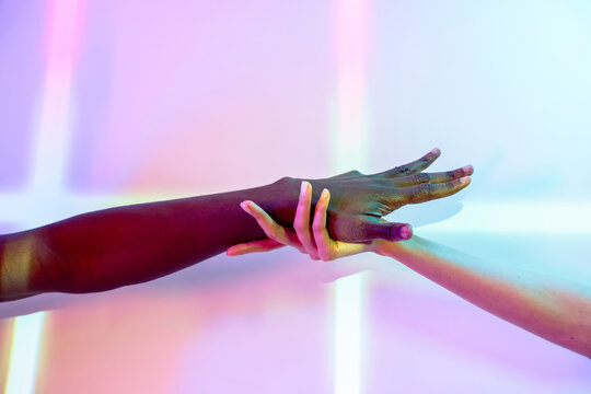 Multiethnic hands in vibrant colored light