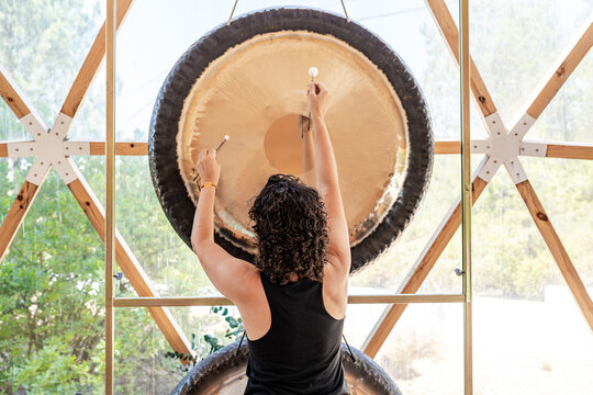 Sound therapist playing gong in a peaceful setting