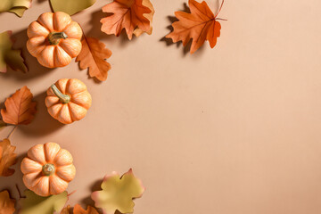Seasonal decoration featuring pumpkins and autumn leaves on a neutral background