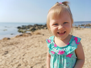 Portrait of a Little Blonde Girl Smiling on a Summer Beach Background