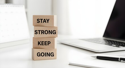 Motivational message "Stay Strong Keep Going" on wooden blocks at office desk