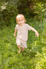 Little boy running barefoot through the green grass