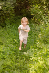 Little boy running barefoot through the green grass