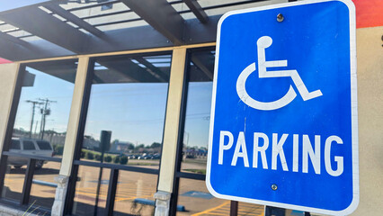 blue parking sign featuring a universal symbol for accessibility and the word PARKING. Highlights the availability of designated spaces for differently disabled individuals for convenience.