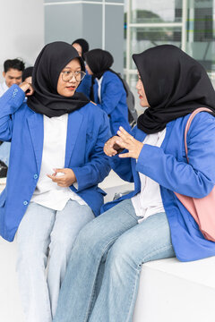Asian female students chatting on campus bench