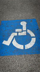 blue handicapped parking symbol painted on an asphalt surface, representing accessibility and inclusivity for people with disabilities. Rustic disabled parking sign
