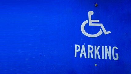 blue parking sign featuring a universal symbol for accessibility and the word PARKING. Highlights the availability of designated spaces for differently disabled individuals for convenience.