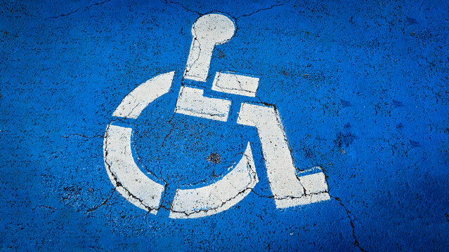 blue handicapped parking symbol painted on an asphalt surface, representing accessibility and inclusivity for people with disabilities. Rustic disabled parking sign