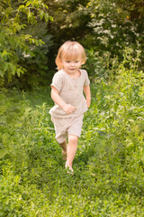Child exploring nature, seated on a log amidst green vegetation.