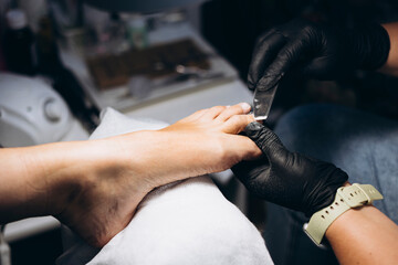 Close-up of female foot during hygienic pedicure under lamp light.