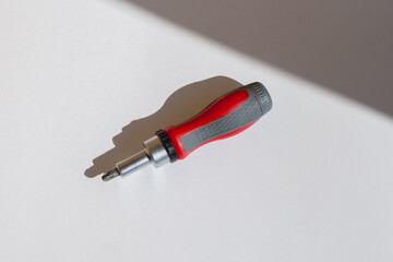 Ratchet screwdriver lying on a white background close-up, ratchet screwdriver ready for work, construction tool on white background, screwdriver as a symbol of repair or renovation work